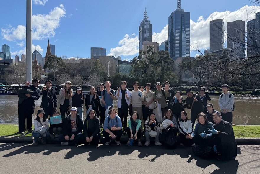 Group of people beside the Yarra River with city buildings in the background.