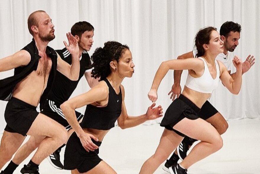 People wearing jogging shorts and tops, running in a white space.