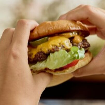 Hands holding a burger.