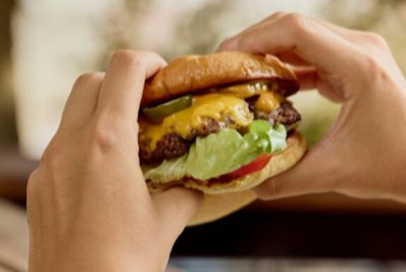 Hands holding a burger.