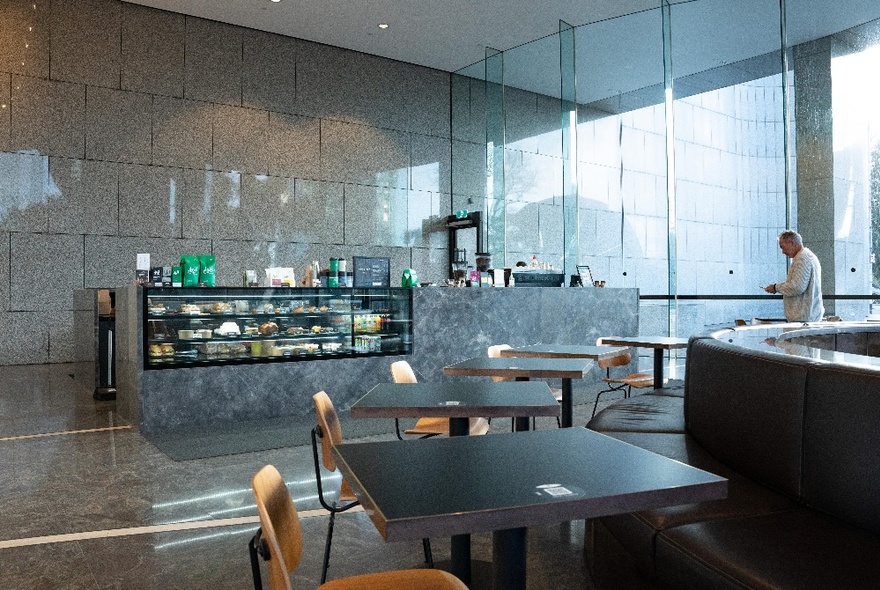 The counter of Axil Coffee on the ground floor of a corporate building, with some chairs and tables in the foreground.