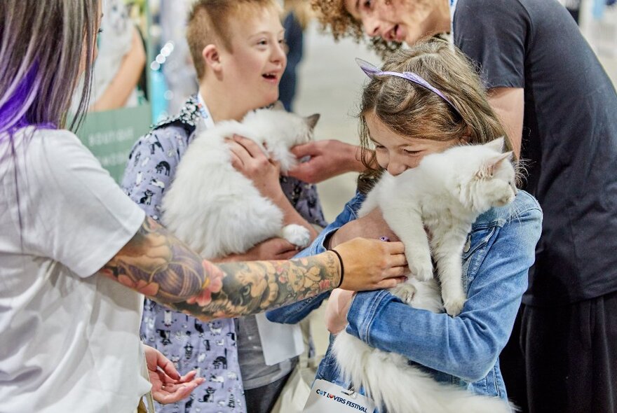 Two young children holding and petting cats at the Cat Lovers Festival.