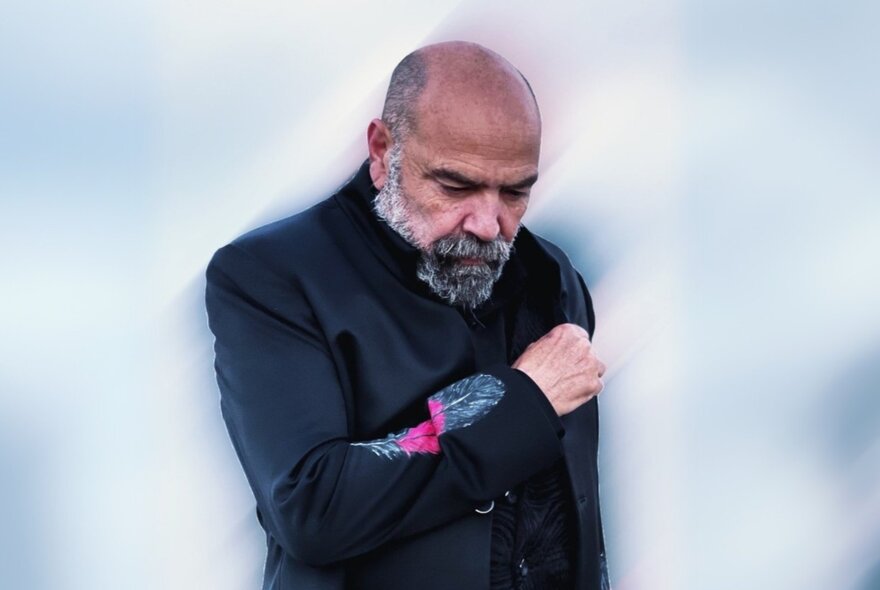 Gunditjmara artist and veteran Richard J Frankland looking downwards with his fist clenched across his chest.