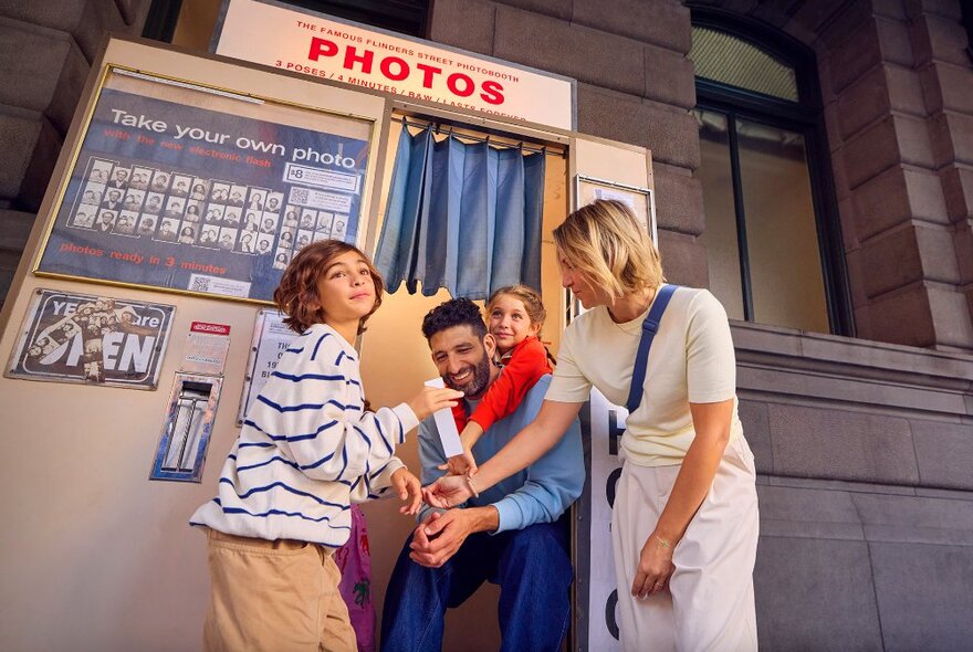 A family posing outside a retro photobooth.