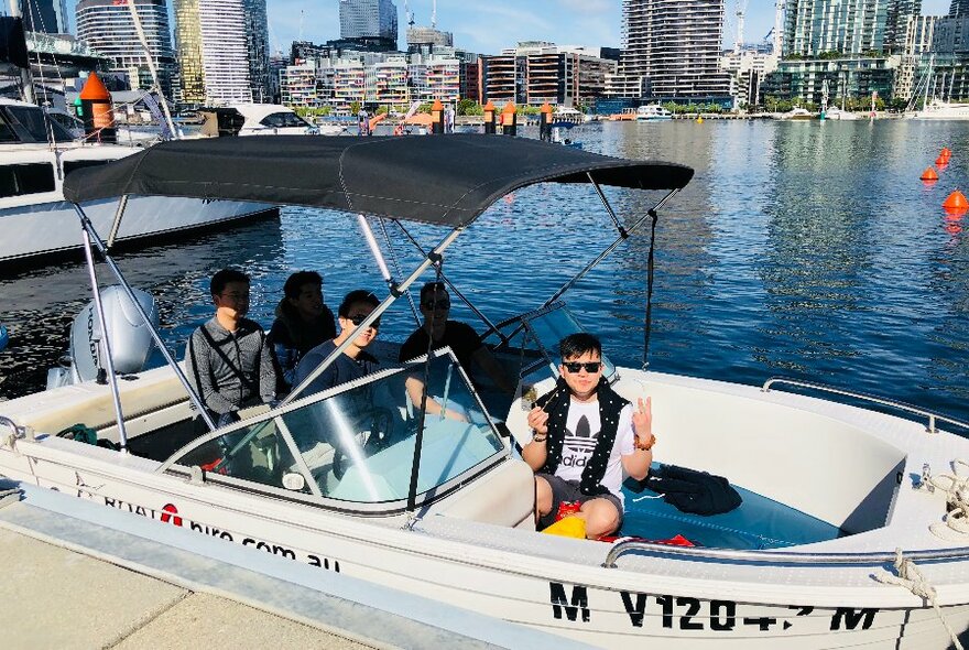 Five passengers onboard a fishing speed boat on a sunny day.