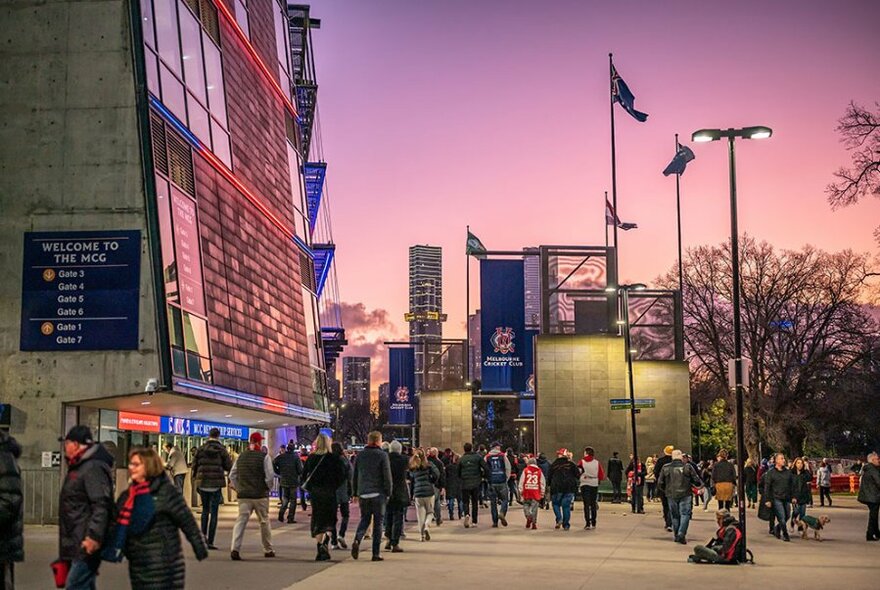 People milling around the MCG at dusk.