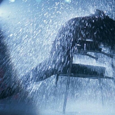 A scene from the film Flashdance with a dancer in silhouette leaning back in a chair, a spotlight behind them, surrounded by water droplets.