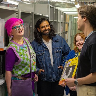 Three people listening to a tour guide as they tour the archives of the State Library of Victoria.