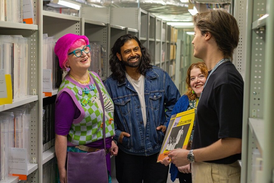 Three people listening to a tour guide as they tour the archives of the State Library of Victoria.