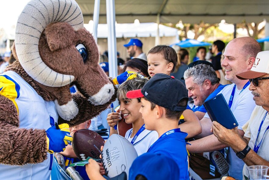 The LA Rams mascot, Rampage, greeting fans and signing NFL footballs.