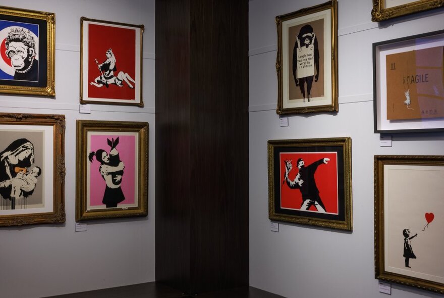 Inside a gallery with Banksy artwork in small frames on the walls. 