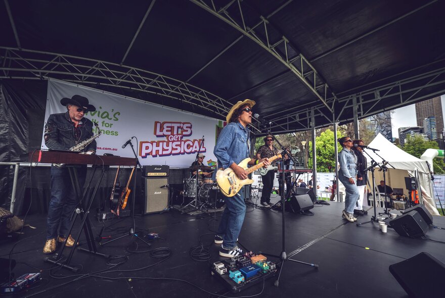 Live band performing under a roof in an outdoor setting.