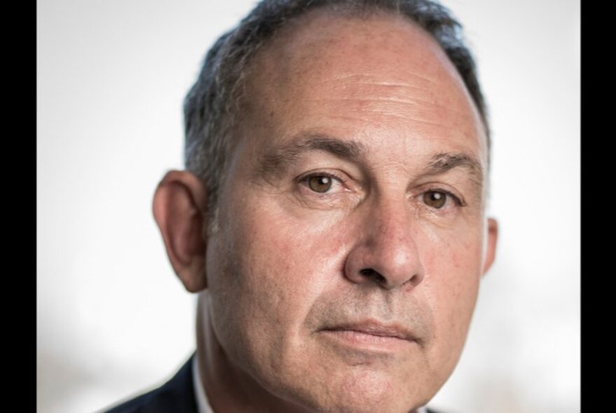 Portrait of Adam Courtenay, a middle-aged man, looking directly at the viewer with a neutral expression on his face.