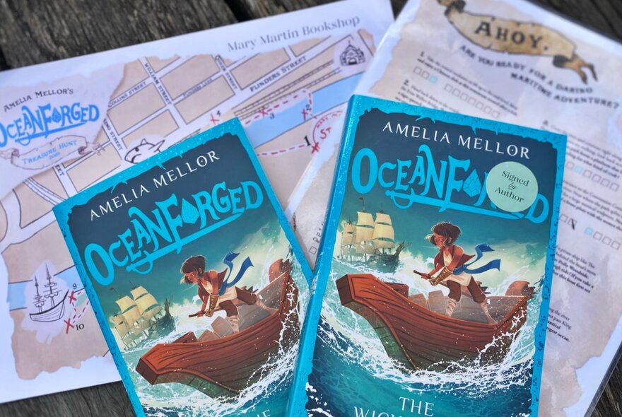 Two copies of Amelia Mellor's book, Oceanforged, with a treasure map and instruction sheets.