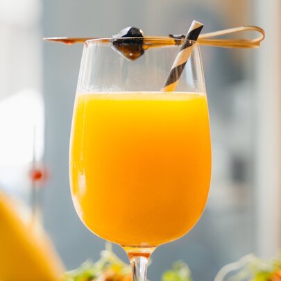 A wine glass with orange mimosa and a tooth pick on top.