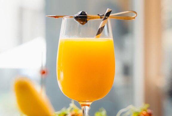 A wine glass with orange mimosa and a tooth pick on top.