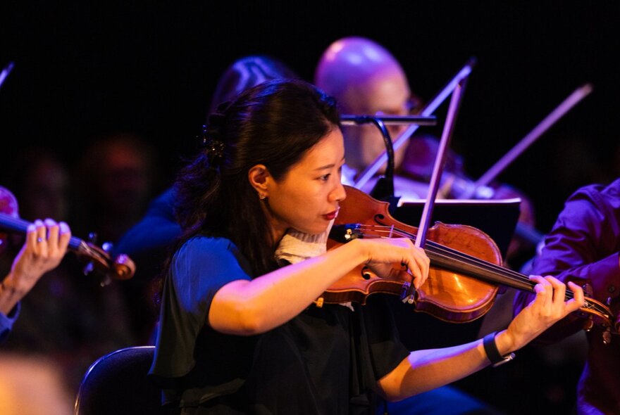Violinist from Orchestra Victoria performing with others in the background. 
