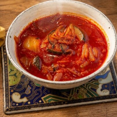 Bowl of spicy red chill soup on a table.