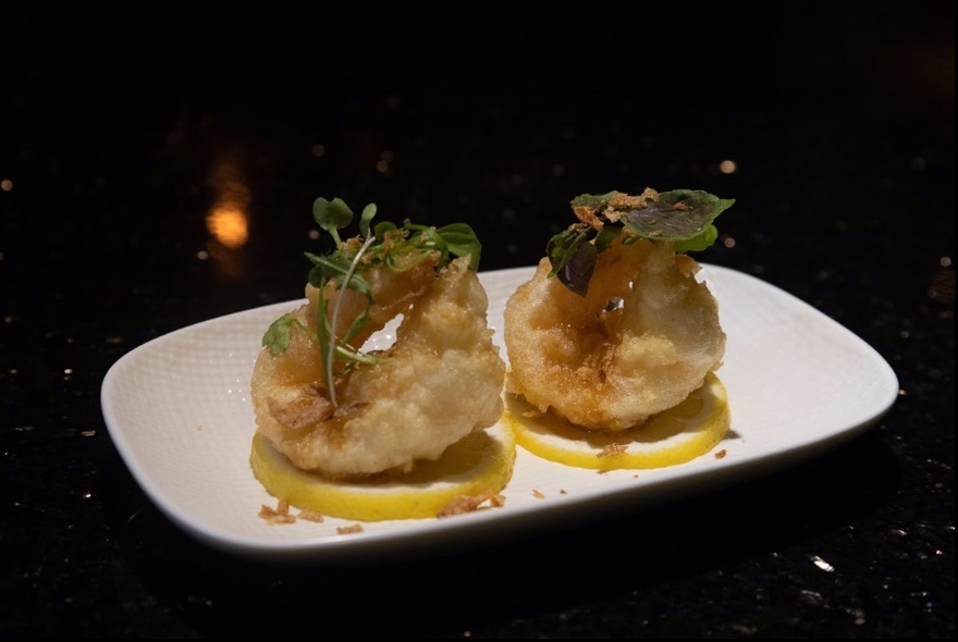 White plate with two appetisers resting on lemon slices.