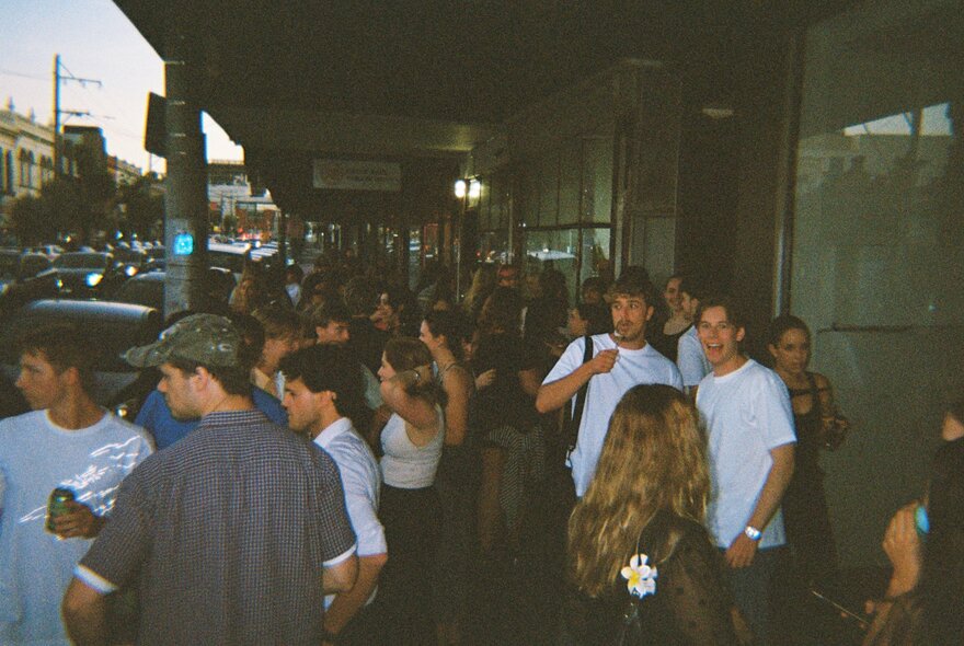 Crowds queuing outside a store on a busy street.