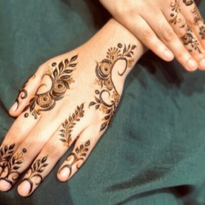 Hands with henna tattoos on a background of green material. 