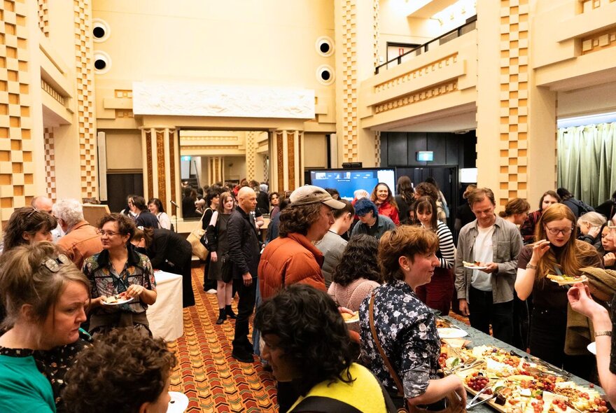 People inside the art deco Capitol Theatre foyer eating canapes.