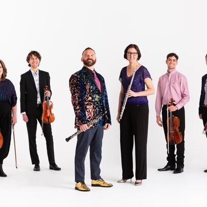 The six musicians of the Inventi Ensemble, standing against a white background and all holding musical instruments.