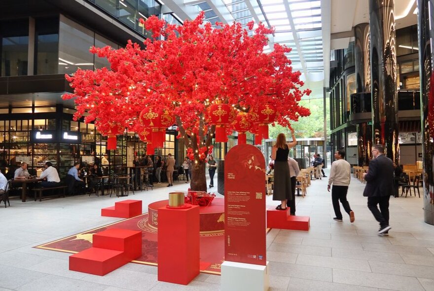 A red tree with leaves made from red paper messages in Collins Square. 