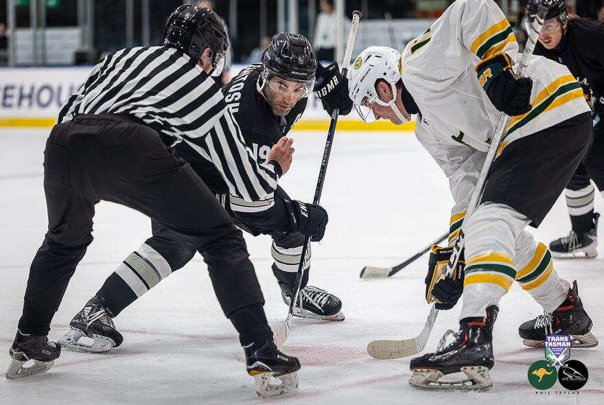 Australia and New Zealand ice hockey players face off at the beginning of a game.