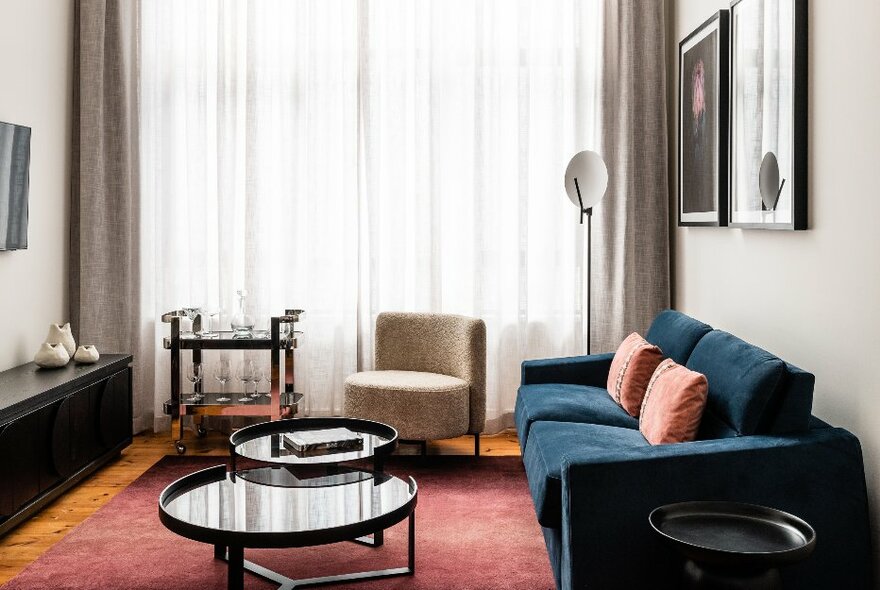 Hotel room lounge space with sofa, lamp, chair and tables.