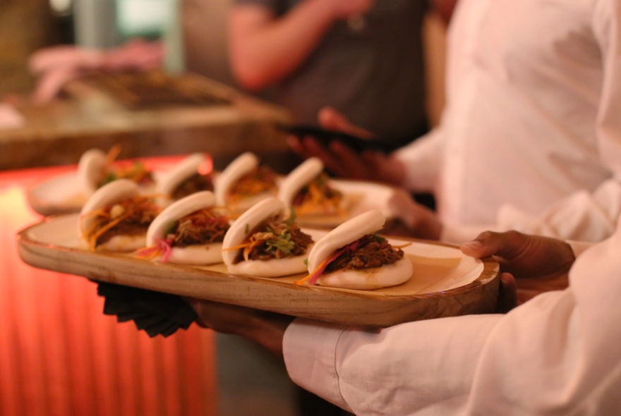 Waiter holding a tray of bao buns.