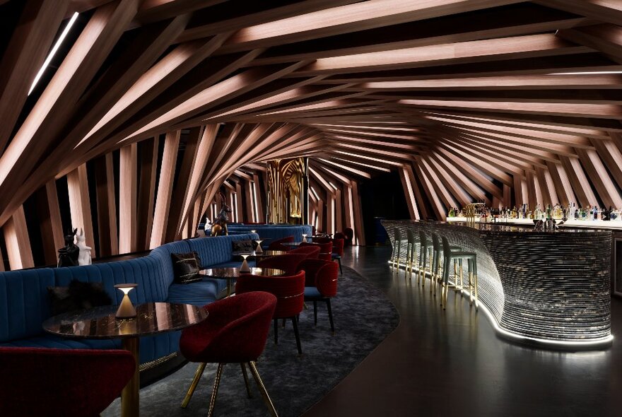 The cocoon-like interior space of Curious bar, with a textured wall and ceiling, and small groupings of round tables and club chairs.
