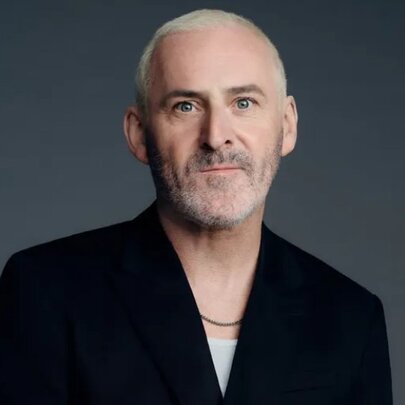 Hairdresser Shay Dempsey sitting looking neutral in a black blazer. 