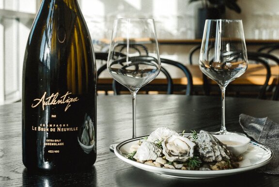 Wine bottle and glasses with a plate of oysters.