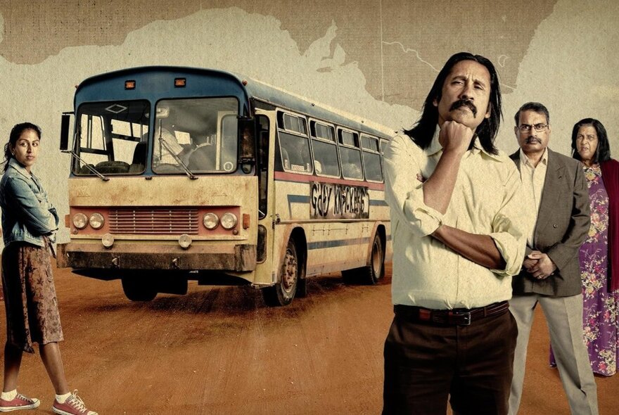 Four Indian tourists standing in front of an old tour bus in the desert.