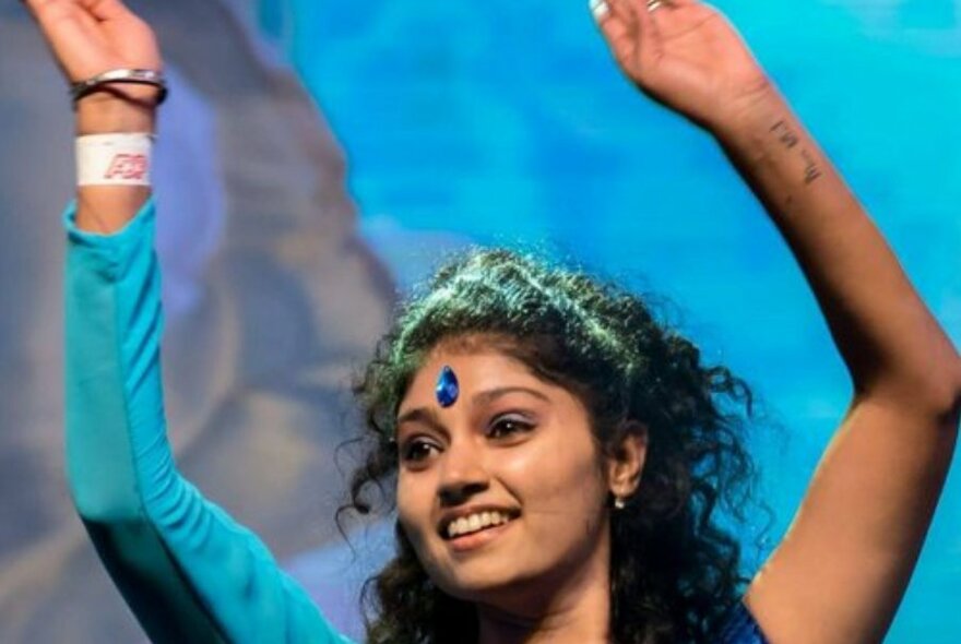 Indian dancer waving her hands in the air while dancing.