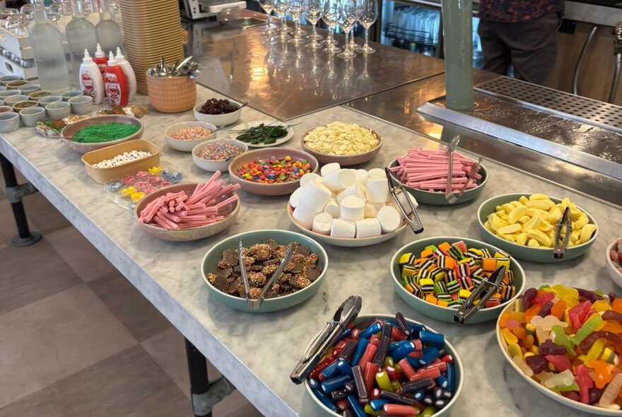 A counter filled with bowls of different sweets.