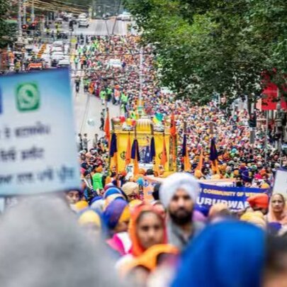 A large crowd of people in bright colours marching down a street with placards. 