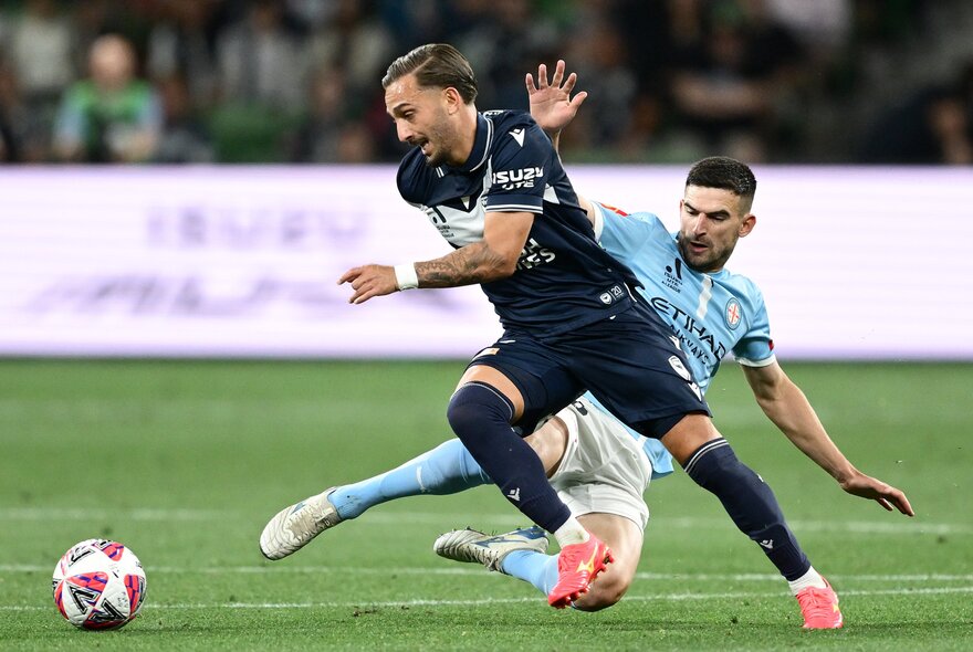 Soccer players kicking and falling with the ball during a match.