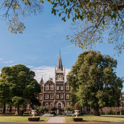 Deaf Children Australia's historic Bluestone building with a pointy tower in a large garden setting. 