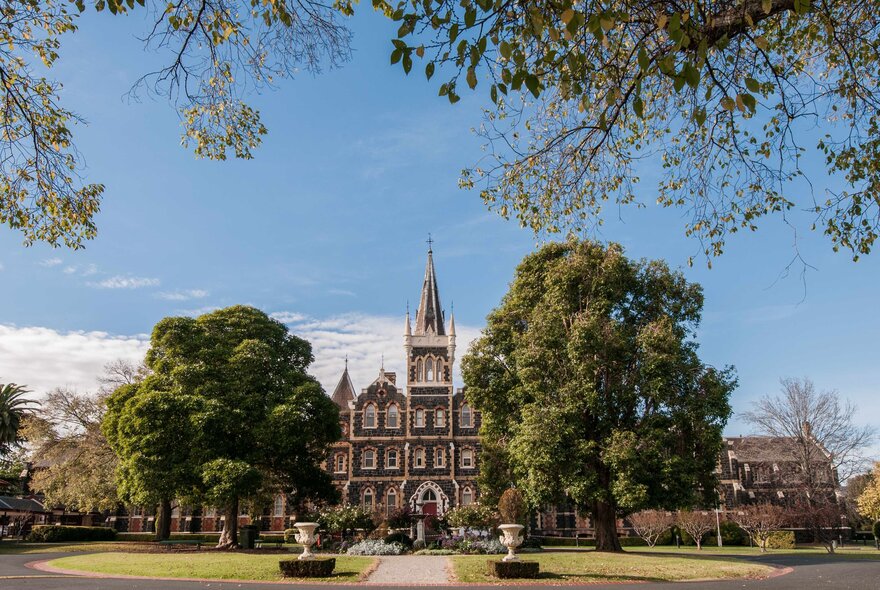Deaf Children Australia's historic Bluestone building with a pointy tower in a large garden setting. 