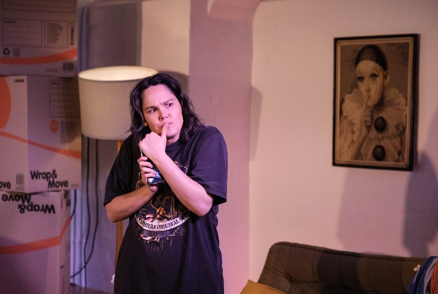 Comedian, Jenna Suffern, standing in a living room with her thumb to her mouth, looking puzzled.