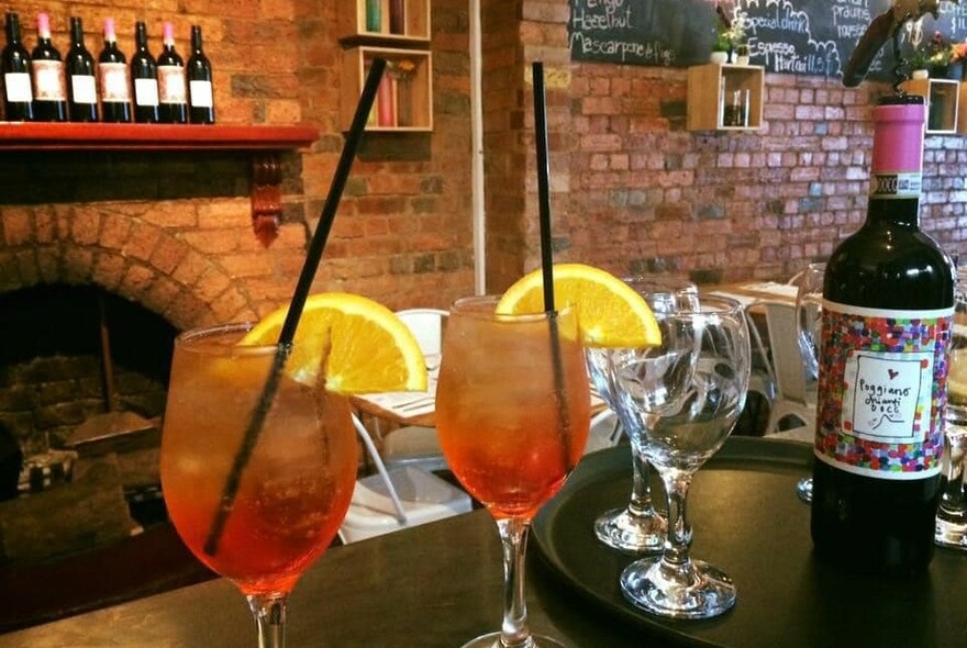 Cosy restaurant setting with drinks and wine bottle.