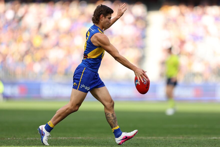 A West Coast Eagles AFL football player lining up to kick the football during a match.