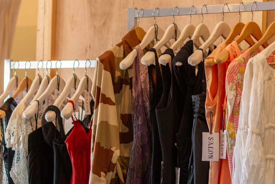 Racks of clothing on wooden hangers.