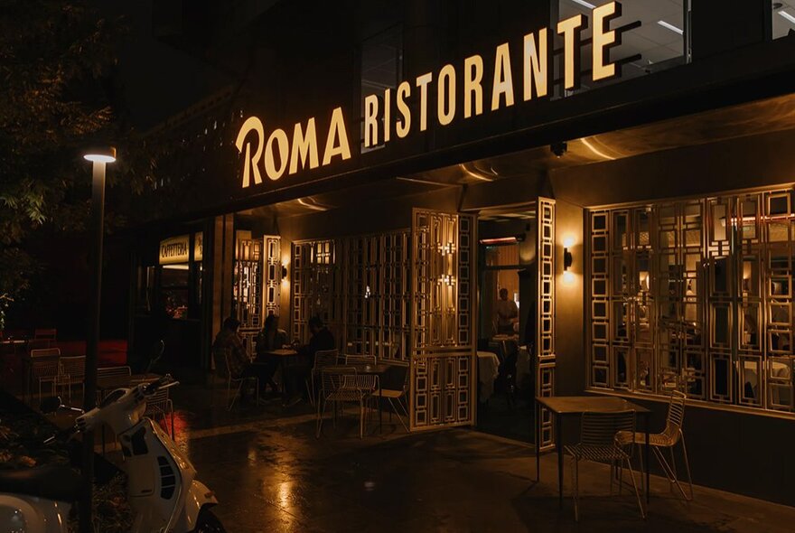 A restaurant entrance at night with a sign that reads, Roma Ristorante.