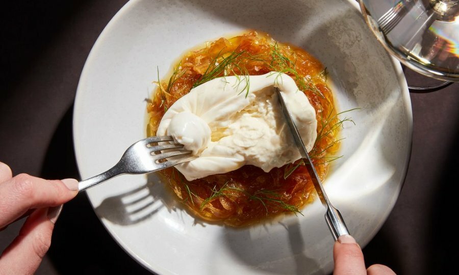 A knife and fork cutting into a soft ball of cheese