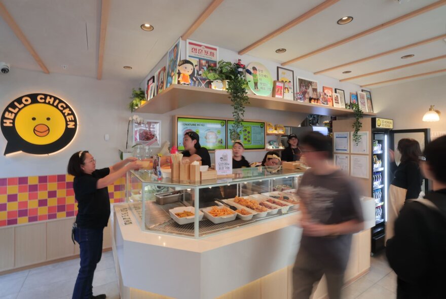 The interior of Hello Chicken, with a glass counter and food behind it.