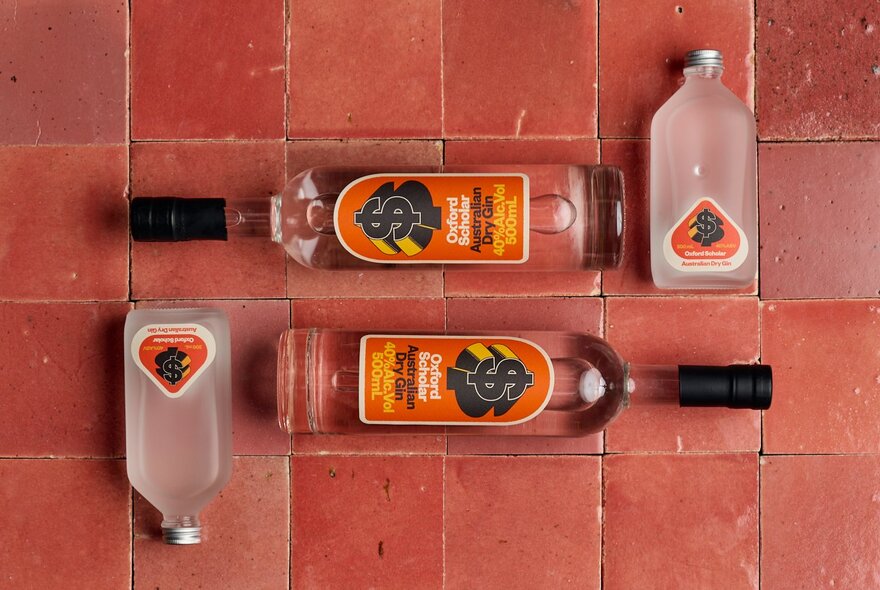 Looking down at bottles laid flat on a reddish-brown tiled background.