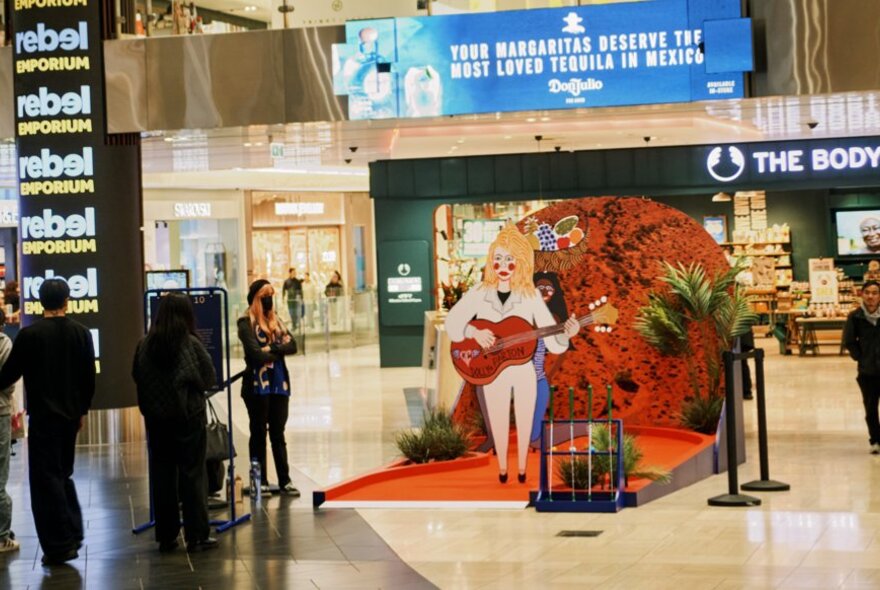 A pop-up mini golf installation in a shopping centre with a large cut-out Dolly Parton. 